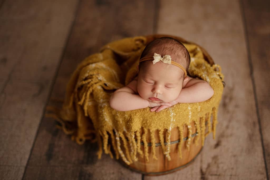 baby in bucket with yellow blanket