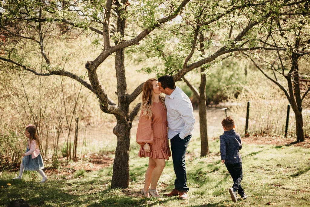 mom and dad capture a kiss while the kids run around 