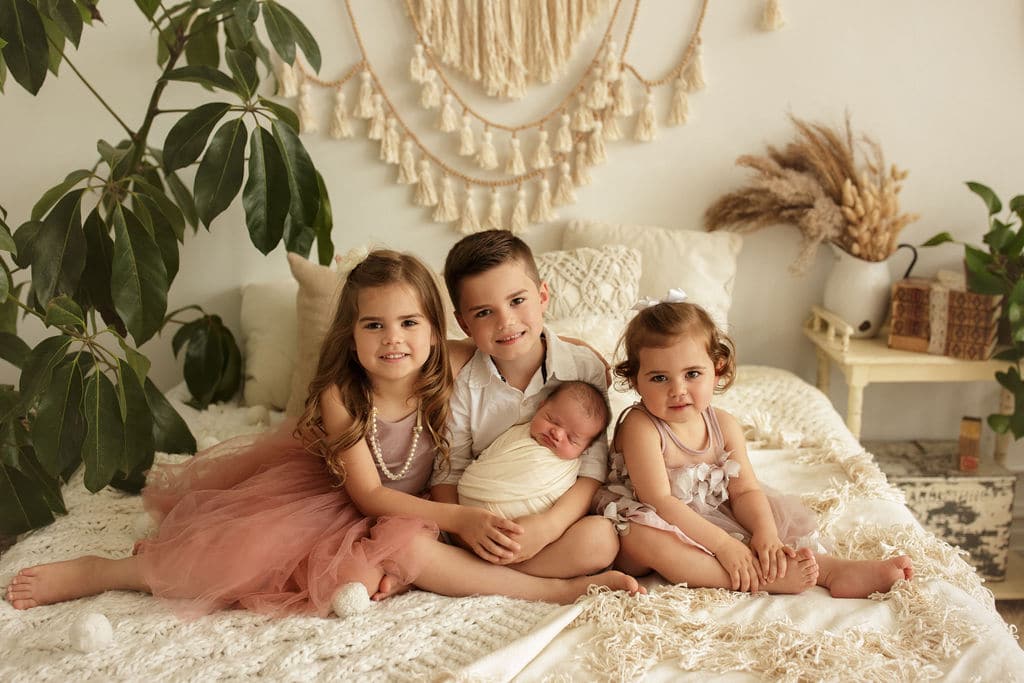 sweet siblings holding their baby brother