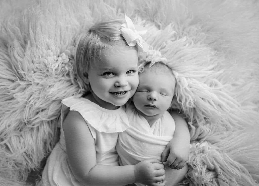 big sister holding little brother, black and white